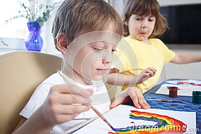 Children engaged in creativity in the home interior. Child draws and colors the picture with paints and a brush Stock Photo