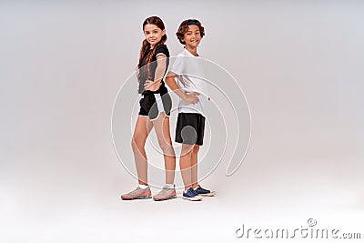 Children engaged in sport. Two teenagers, cute boy and girl in sportswear looking at camera and smiling while posing Stock Photo