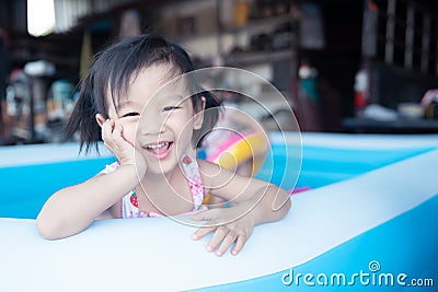 Children enjoy and have fun playing water in inflatable pool with colorful of small balls Stock Photo