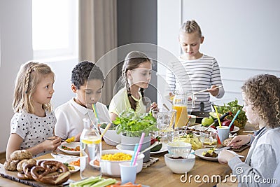 Children enjoying a healthy meal by a table in a dining room during a lunch break in a private primary school Stock Photo