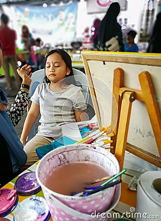 Children face painting. Artist painting little girl at the shop Stock Photo