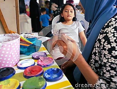 Children face painting. Artist painting little girl at the shop Stock Photo