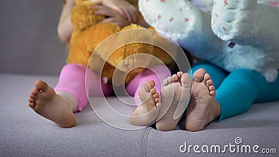 Children feet closeup, multiracial friends sitting on sofa, playing with teddies Stock Photo