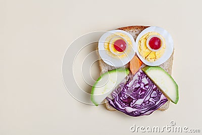 Creative and funny tasty sandwich for breakfast, cute owl made of toast bread decorated with eggs and vegetables, copy space, top Stock Photo