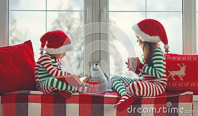 Children girl and boy in pajamas is sad on Christmas morning by window Stock Photo