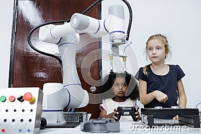 Children girl caucasoid and girl African American education electronic robotic arm on table at class room Stock Photo