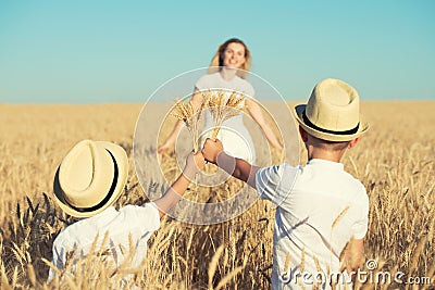 Children give their mother bouquet of spikelets in a wheat field. Stock Photo