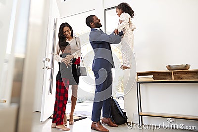 Children Greeting And Hugging Working Parents As They Return Home From Work Stock Photo