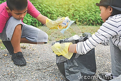Children hand in yellow gloves picking up empty of bottle plastic into bin bag Stock Photo