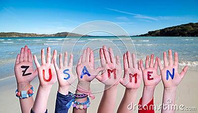 Children Hands Building Word Zusammen Means Together, Sea And Ocean Background Stock Photo