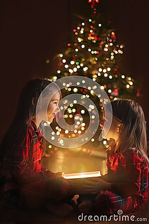 Children happily look at each other opening magic gift boxes at midnight on Christmas eve. Stock Photo