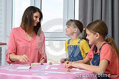 Children happily looked at mom playing board games Stock Photo