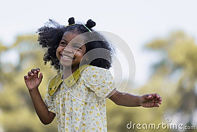 African black child with curly hair is jumping happily in the water spray at outdoor Stock Photo