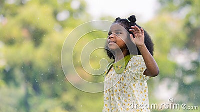 African black child with curly hair is jumping happily in the water spray at outdoor Stock Photo