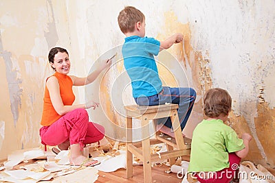 Children help mother remove old wallpapers Stock Photo