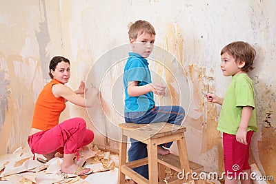 Children help mother remove old wallpapers from wa Stock Photo