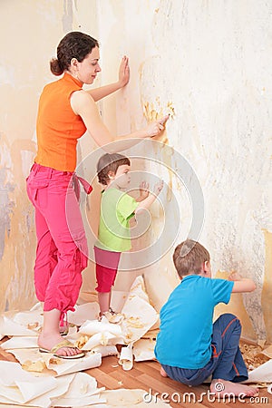 Children help mother remove from wall old wallpap Stock Photo