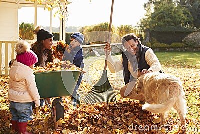 Children Helping Parents To Collect Autumn Leaves In Garden Stock Photo