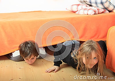 Children hiding under bed Stock Photo