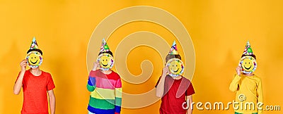 Children in a holiday cap stand in a row and hold a smiling emoticon at face level. The concept of a children`s holiday and fun Stock Photo