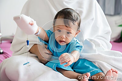 Children illness . Little Baby attaching intravenous tube to patient`s hand in hospital bed. Baby sick and crying on mom . Stock Photo