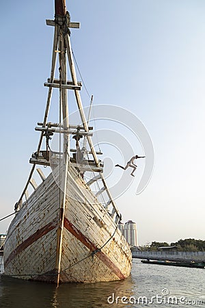 Children jumping into the water from the wooden boats in Jakarta harbor Editorial Stock Photo