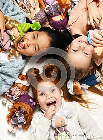 Children kids playing in kindergarten girls lying on a floor with little doll toys happy screaming laughing Stock Photo