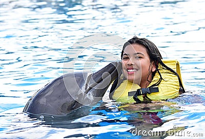 Children kissing dolphin in pool Stock Photo