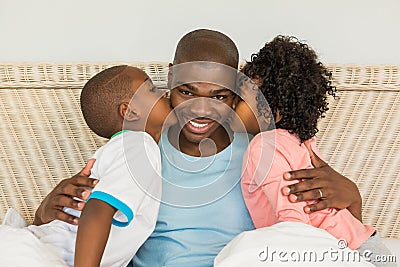 Children kissing father in bed Stock Photo