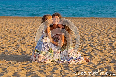 Children kissing and hugging mother at the beach. Stock Photo