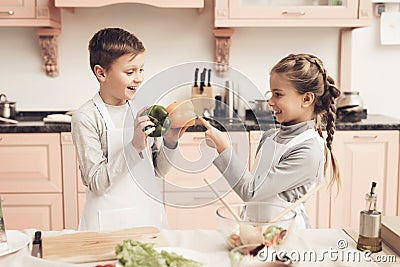 Children in kitchen. Brother is holding peppers and sister is choosing. Stock Photo