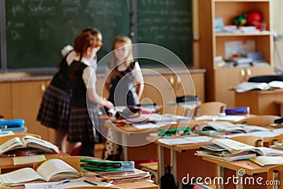 The children left their satchels and notebooks on the tables and went to recess. Three small students stayed in class to discuss Stock Photo
