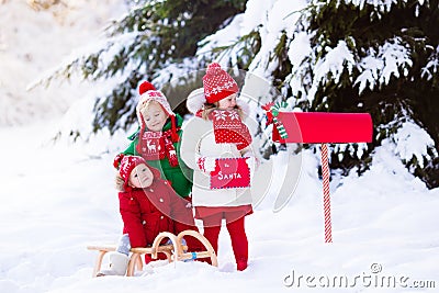 Children with letter to Santa at Christmas mail box in snow Stock Photo