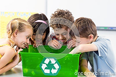 Children looking at plastic bottles in recycling box Stock Photo