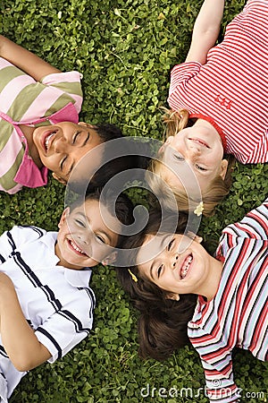Children Lying in Clover With Heads Together Stock Photo