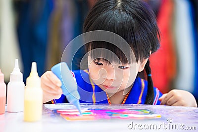 Children make crafts. Girl make art by dripping paint from plastic bottles. Child learn to make art from watercolor. Stock Photo