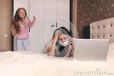 Children make it difficult to focus on work. mother in protective mask working from home during quarantine time at coronavirus. Stock Photo
