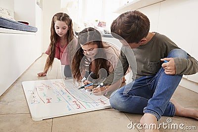 Children Making List Of Chores On Whiteboard At Home Stock Photo