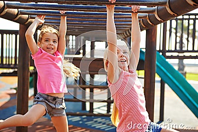 Children need the freedom and time to play. two little girls hanging on the monkey bars at the playground. Stock Photo