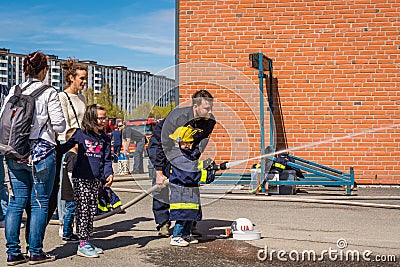 Children and parents at a fire station trying a fire hose. Editorial Stock Photo