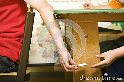 Children passing note under the table. Conceptual image shot Stock Photo