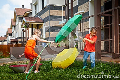 Children playing with garden sprinkler. Brother and sister running and jumping. Summer outdoor water fun in backyard Stock Photo