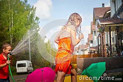 Children playing with garden sprinkler. Brother and sister running and jumping. Summer outdoor water fun in backyard Stock Photo