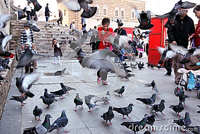 Children play among the pigeons next to Yeni Camii (New Mosque), Eminonu, Istanbul, Turkey. Editorial Stock Photo