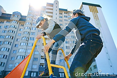 Children play on the playground next to a condominium. Swing, slide, stairs, multistory building. A place for children to play. Stock Photo