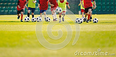 Children play soccer at grass sports field. Football training for kids. Children running and kicking soccer balls at soccer pitch Stock Photo