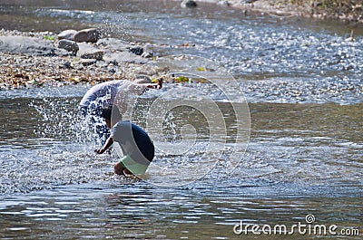 Children play splashing water in the natural creek. Editorial Stock Photo