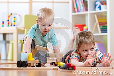 Children play with wooden train and build toy railroad at home, kindergarten or daycare Stock Photo