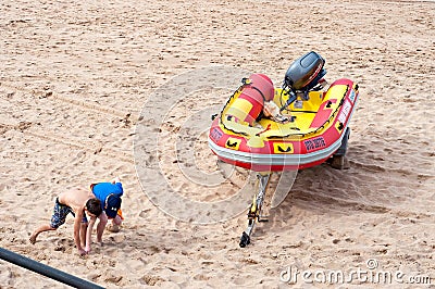 Children playing on the beach near a surf rescue boat in Umhlanga Rocks Editorial Stock Photo