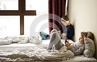 Children playing in bed with their tablets and phones Stock Photo